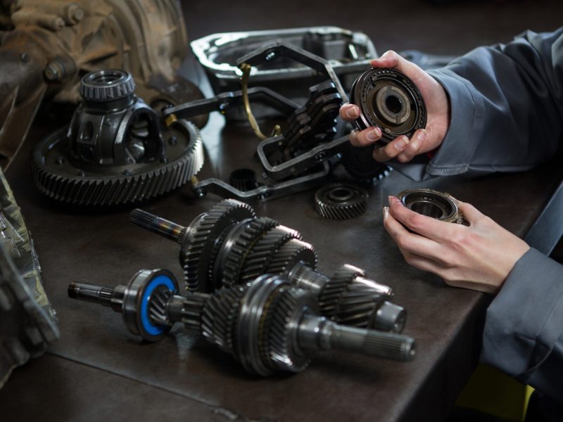 Close-up of female mechanic holding spare parts of car at repair garage