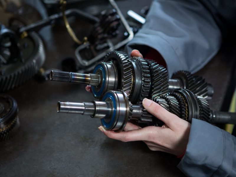 Close-up of female mechanic holding spare parts of car at repair garage